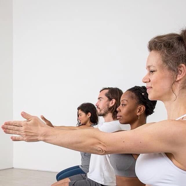 Pilates class practising together with arms extended